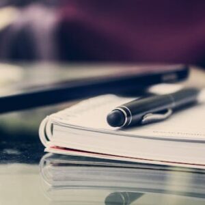 Close-up of an elegant pen resting on an open notebook in a stylish office environment.